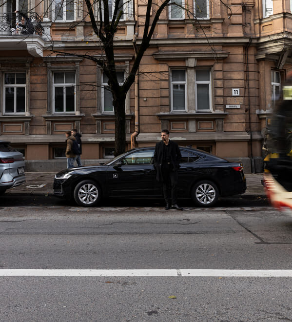 ADMITA car rental with delivery – man standing next to a black car in the city