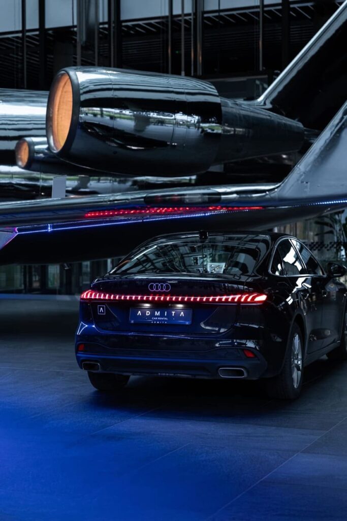 Juodas Audi automobilis su Admita logotipu prie modernaus verslo centro pastato | ADMITA