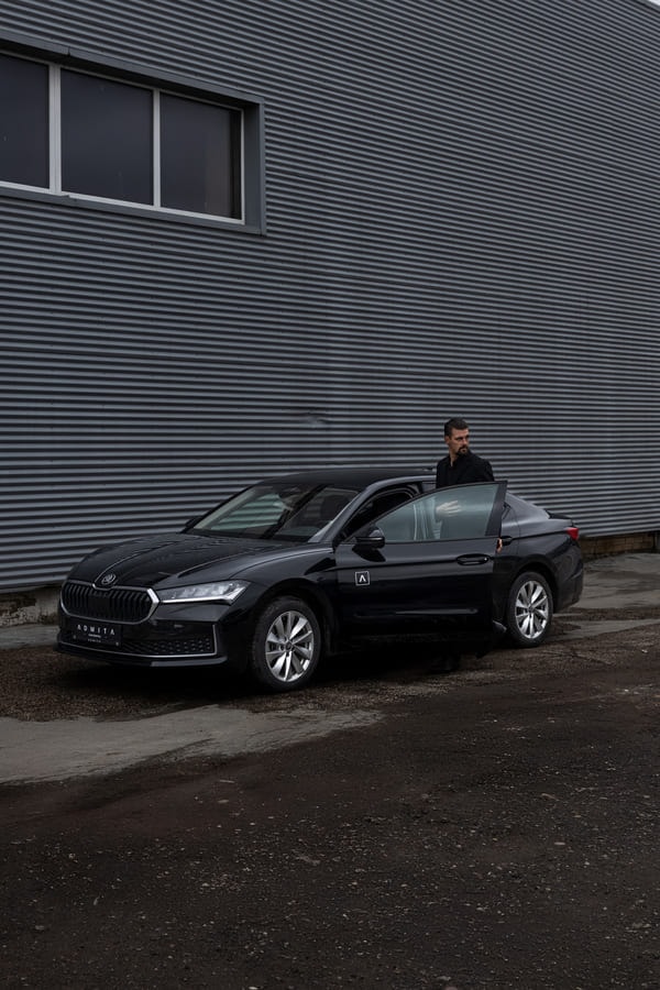 Ilgalaikė automobilių nuoma ADMITA – vyras prie juodo automobilio mieste