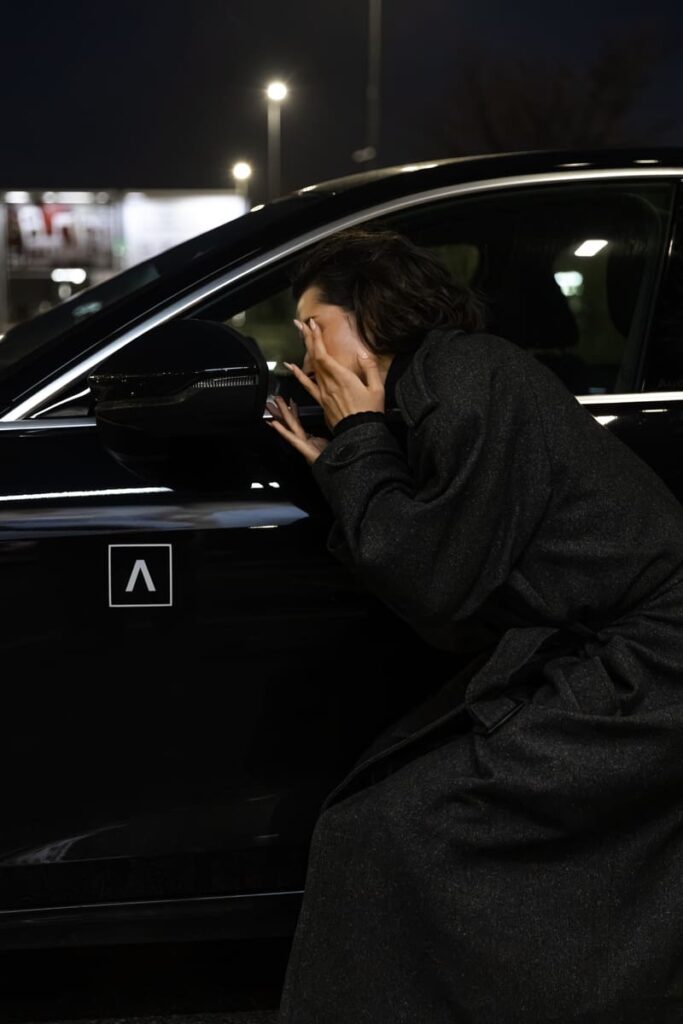Trumpalaikė automobilių nuoma ADMITA – moteris prie automobilio naktį