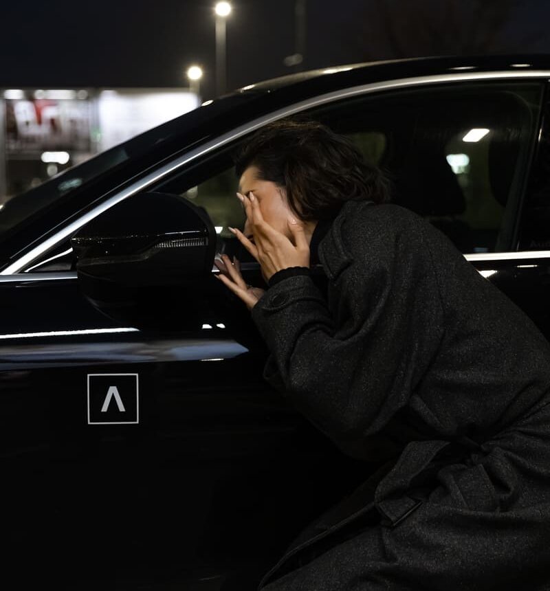 Trumpalaikė automobilių nuoma ADMITA – moteris prie automobilio naktį